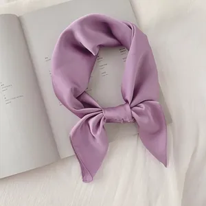 Gros plan d'un élégant foulard en satin violet sur fond de magazine minimaliste
