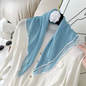 Detail view of light blue pleated scarf featuring an elegant white contrasting trim texture.