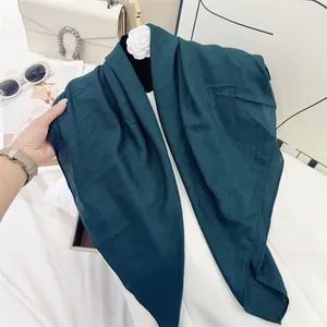 Detailed view of dark teal crinkled cotton feel square scarf with soft texture