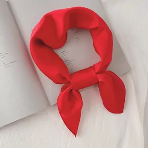 Gros plan d'un foulard en soie rouge vif noué avec élégance sur un magazine