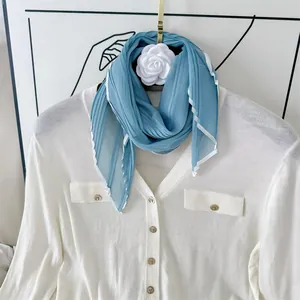 Detail of light blue pleated silk scarf with white contrast border and elegant texture