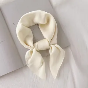Vue détaillée d'un élégant foulard carré en soie crème uni noué avec un nœud chic