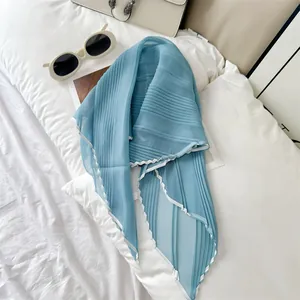 Close-up of elegant blue pleated scarf with white contrast piping on white background.
