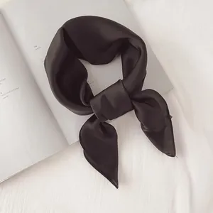 Gros plan d'un foulard carré noir minimaliste en satin avec une texture soyeuse