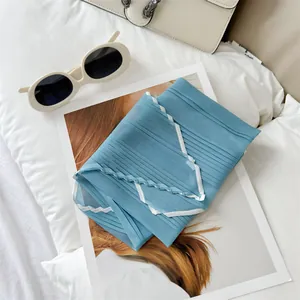 Close-up detail of a light blue silk scarf featuring elegant white pleated borders