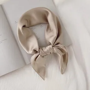 Vue détaillée d'un luxueux foulard carré en soie champagne avec un nœud élégant