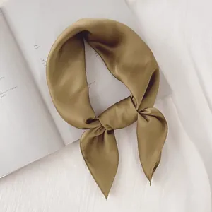 Élégant foulard en satin de soie vert olive noué sur un fond minimaliste et épuré