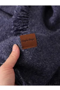 Detalle de un chal de punto azul oscuro con una etiqueta de marca de cuero premium