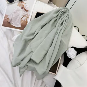 Detailed view of a soft sage green scarf featuring a unique natural wrinkled cotton texture