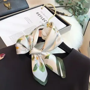 Elegant floral silk square scarf with green border draped on a black blouse for fashion.