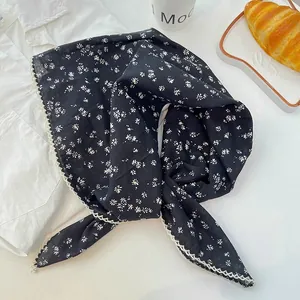Detail of black floral cotton scarf with delicate white scalloped lace edges