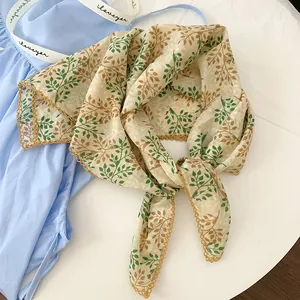 Close-up detail of a cotton leaf print neck scarf with delicate gold lace edging.