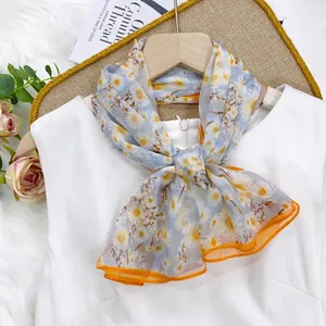 Close-up detail of a thin daisy print summer scarf tied elegantly on a white top.