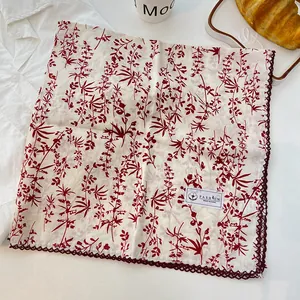 Close-up of a 100% cotton square scarf with red botanical print and lace trim