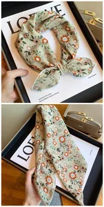 Detail of cotton floral scarf with delicate orange flowers and green leaves pattern.