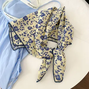Detailed macro view of a floral printed 100% cotton scarf with blue crochet lace trim