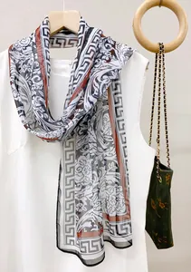 Close-up of elegant long scarf with floral and Greek key pattern in white and black