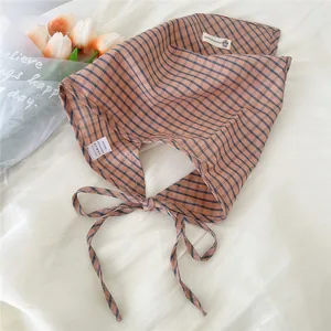 Primo piano di una bandana in cotone a quadretti marroni con elegante laccio per capelli