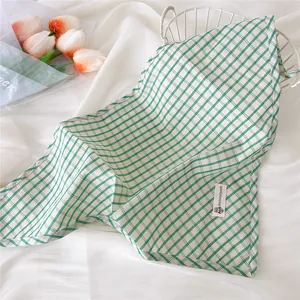 Dettaglio di un foulard a triangolo a quadretti verde chiaro con etichetta chic.