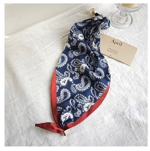 Detailed view of blue and red paisley silk scarf with elegant pearl and gold clasp