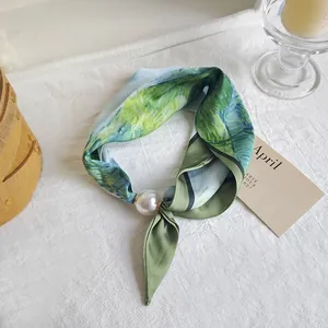 Detailed view of elegant green artistic print silk scarf featuring a large pearl fastener ring