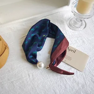 Detailed view of elegant equestrian print silk scarf with a large decorative pearl ornament charm