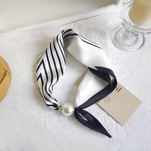 Detail view of a striped black and white silk scarf with a large elegant pearl decoration