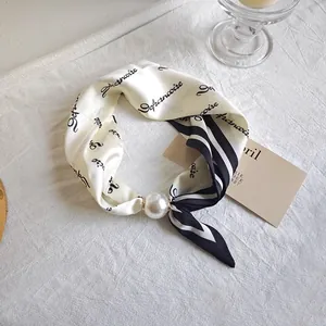 Close-up detail of an elegant black and white silk scarf featuring a large pearl bead