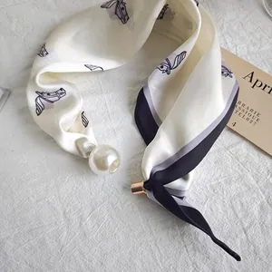 Detailed view of white silk neckerchief featuring horse print and decorative pearl