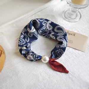 Close-up detail of navy paisley silk scarf featuring elegant large pearl ring slider