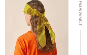 Close-up detail of a Van Gogh Sunflowers print silk scarf styled as a chic headband.