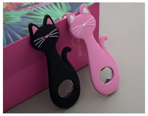 Close-up of black and pink cat-shaped bottle openers leaning against a gift box.
