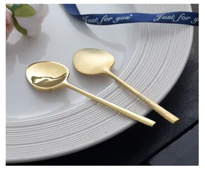 Detailed view of two elegant gold-plated 304 stainless steel coffee spoons on white plate
