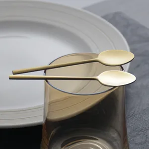 Elegant gold stainless steel coffee spoons set on an amber glass cup and white plate