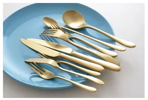 Détail d'un ensemble de couverts en acier inoxydable doré mat sur une assiette bleue