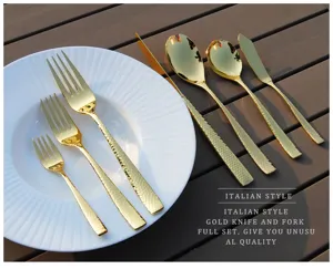 Close-up detail of luxury hammered gold stainless steel cutlery set on a white ceramic plate