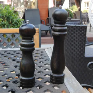 Set of two manual black wooden pepper and salt grinders on outdoor table