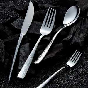 Hammered 304 stainless steel flatware set with steak knife, fork, and spoon on dark rocks