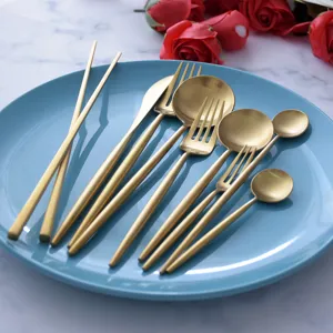 Matte golden 304 stainless steel cutlery set with knives forks and spoons on blue plate