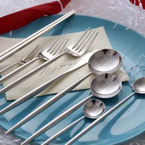 Elegant 304 mirror silver stainless steel cutlery set with round handles on a blue plate