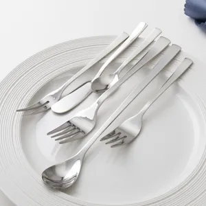 Modern stainless steel cutlery set with spoons forks and knife on a white plate