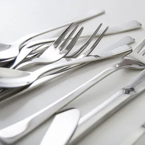 Polished restaurant stainless steel cutlery set with forks, spoons, and knives on white