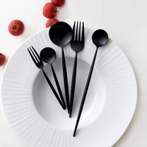5-piece matte black stainless steel cutlery set with minimalist round handles on plate