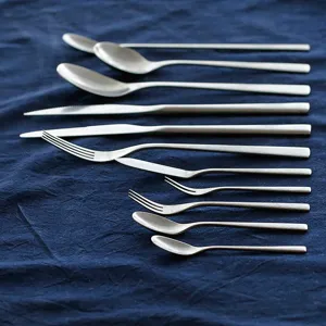 Retro-Besteckset aus gebürstetem 304 Edelstahl mit Messern, Gabeln und Löffeln auf blauem Tuch