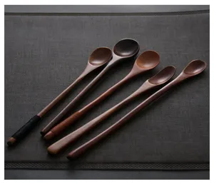 Set of five handcrafted long handle wooden stirring spoons displayed on a textured gray placemat