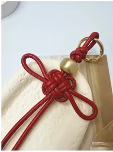 Gros plan détaillé d'un pendentif nœud chinois en similicuir rouge avec perle dorée.