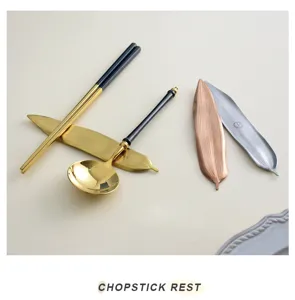 Detail of willow leaf-shaped metal chopstick rests in gold, silver, and copper colors.