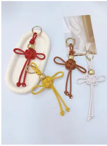 Détail de quatre porte-clés en cuir PU tressés à la main en forme de nœud Ruyi coloré