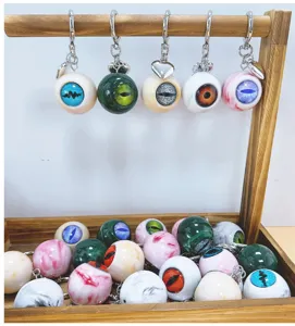 Gothic horror eyeball keychains with metallic heart charms displayed on a wooden stand
