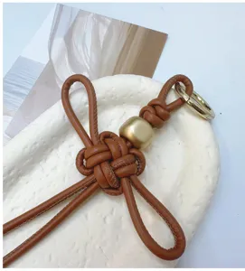 Gros plan d'un pendentif nœud Ruyi en cuir PU marron tressé à la main avec perle dorée